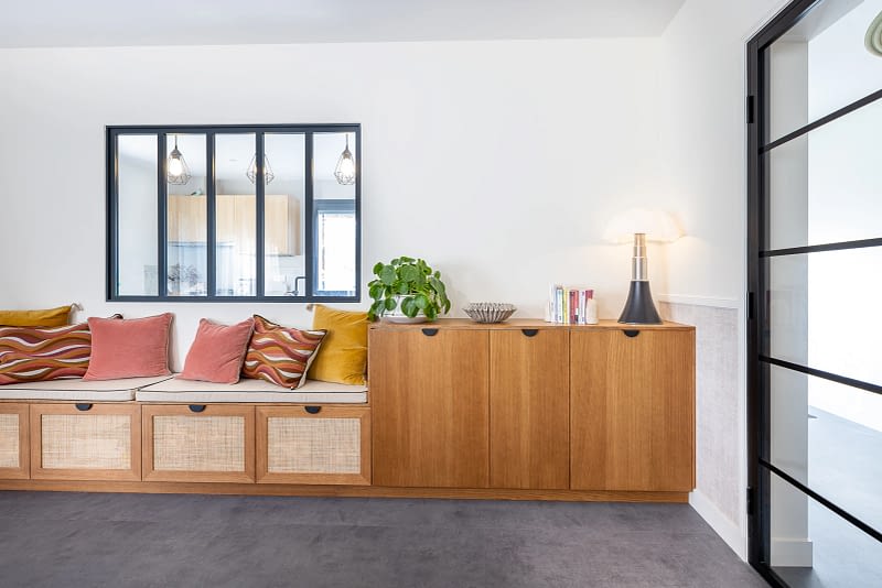 Mobilier sur mesure avec banquette intégrée, buffet de rangement et verrière noire dans un intérieur contemporain